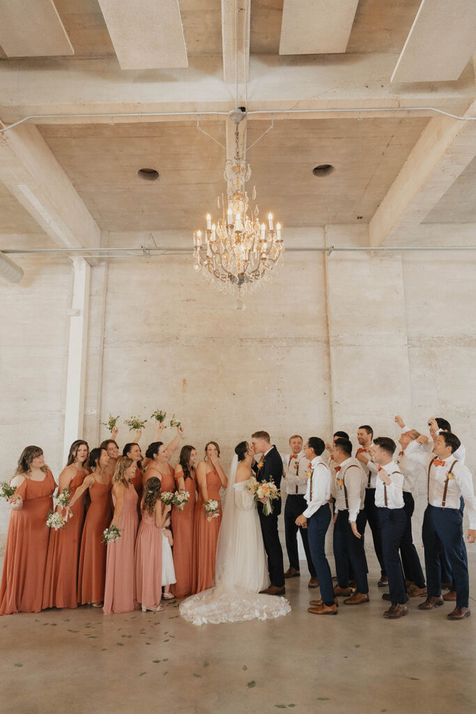 bridal party all together in a concrete room with a chandelier