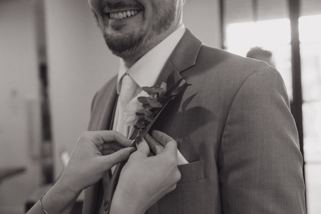 mother attaching grooms boutonniere