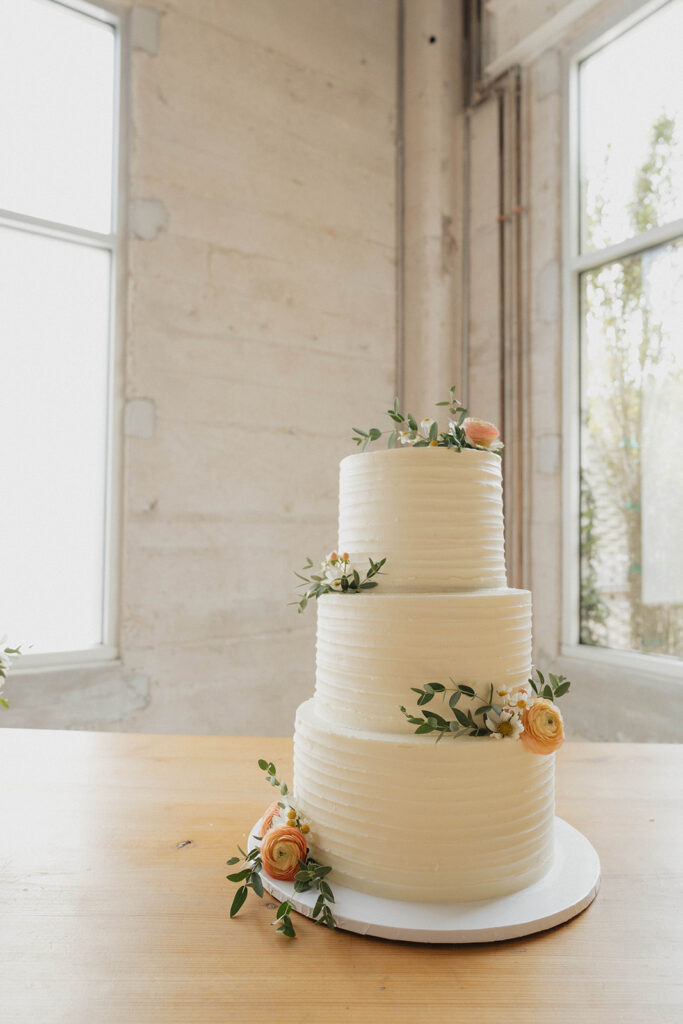 classic white wedding cake with peachy colored florals