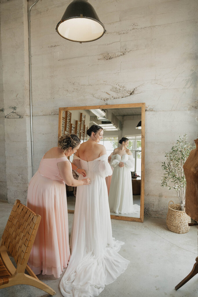 bridesmaid helping bride with wedding dress