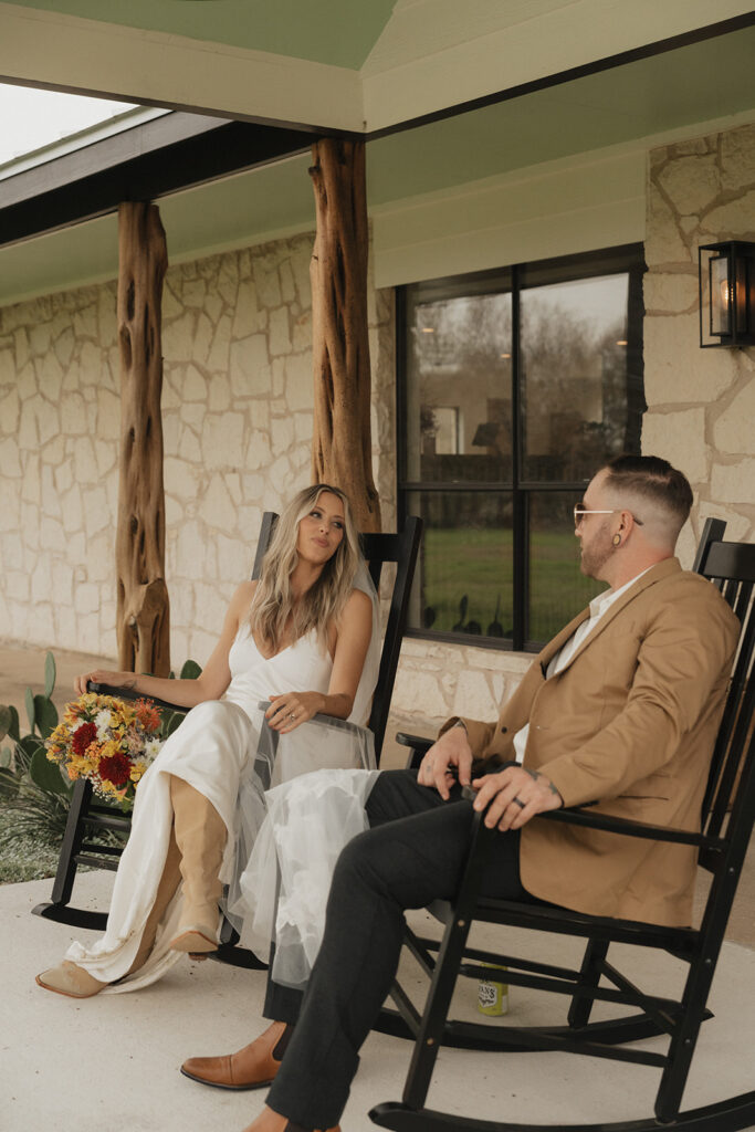 bride and groom sitting on the porch in black rocking chairs at rancho moonrise