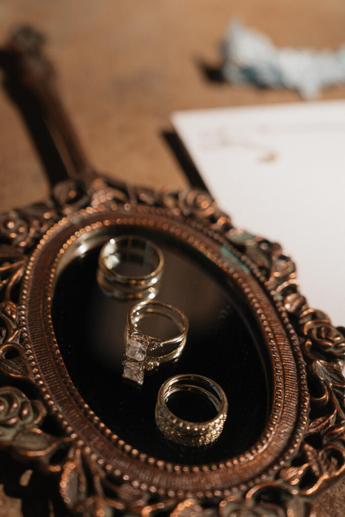 wedding rings laying on a vintage mirror