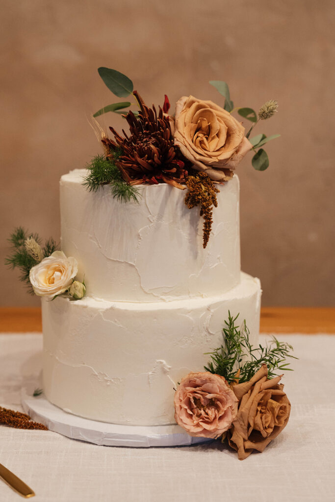 white wedding cake with burgundy and peach florals